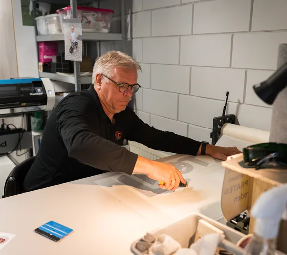 Erik werkt aan stickers aan de werkbank
